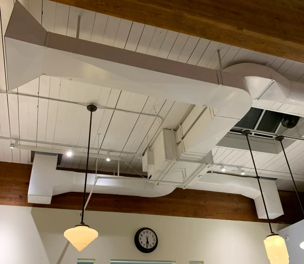 Commercial kitchen ventilation ductwork and exhaust system in industrial space with exposed ceiling beams